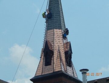 Steeplejacks installing copper shingles to church steeple