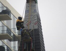 Steeplejacks installing faux slate shingles on church steeple