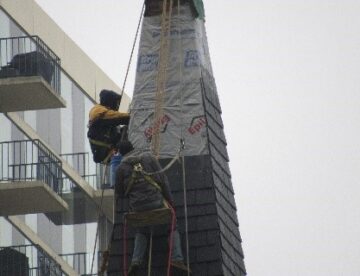 Steeplejacks installing faux slate shingles on church steeple