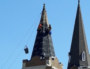 Steeplejack roofer installing a new roof on 2 church steeples